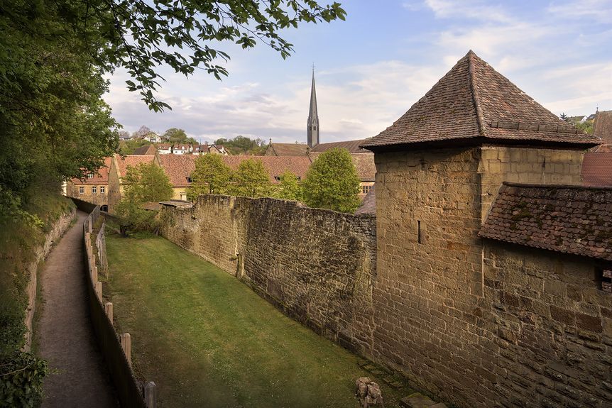 Hohe Mauern und ein Turm, zu sehen von einem Weg aus